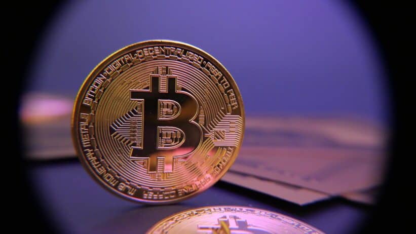 Bitcoin coin displayed on a purple background.