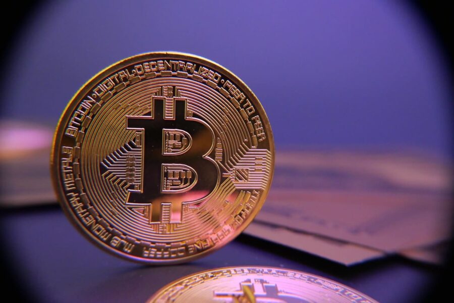 Bitcoin coin displayed on a purple background.