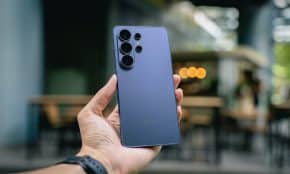 Hand holding a blue smartphone with multiple cameras.