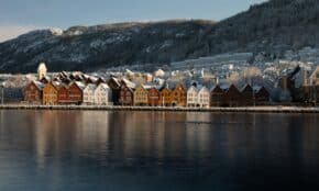 brown and white wooden house near body of water and mountain