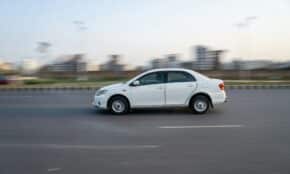 A white car speeds down a road.