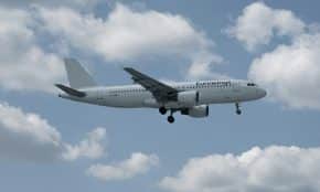 White airplane flying in a cloudy blue sky