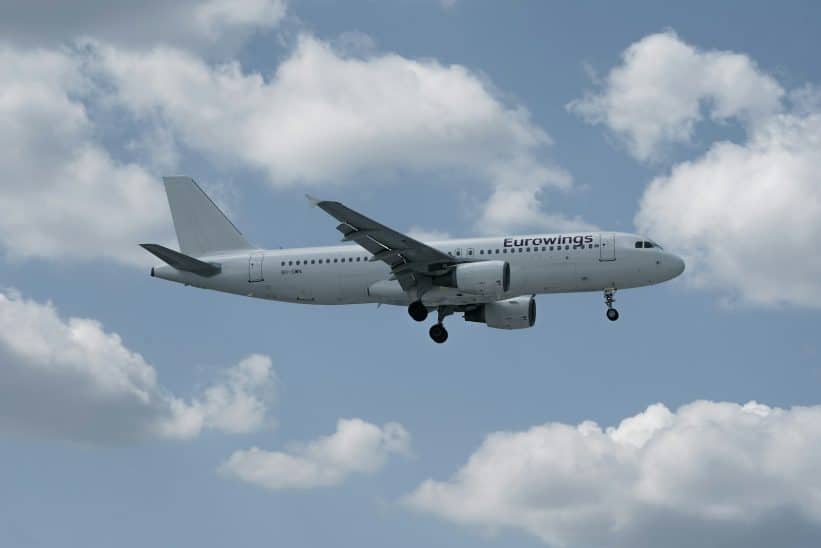 White airplane flying in a cloudy blue sky