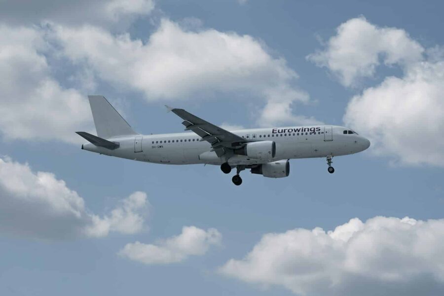 White airplane flying in a cloudy blue sky