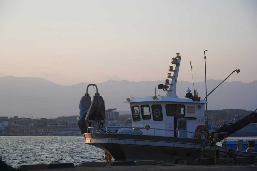 A boat docked at a pier with mountains in the background