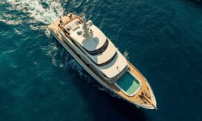 Aerial view of Christina O superyacht, classic 325-foot luxury vessel with teak decking and pool moored in blue Mediterranean waters